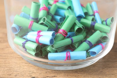 Photo of Colorful paper notes in glass jar on wooden table, closeup