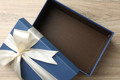 Photo of Opened gift box with beautiful lid on light wooden table, top view