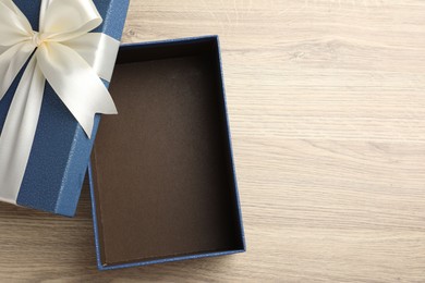 Photo of Opened gift box with beautiful lid on light wooden table, top view. Space for text