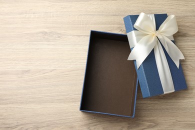 Photo of Opened gift box with beautiful lid on light wooden table, top view. Space for text
