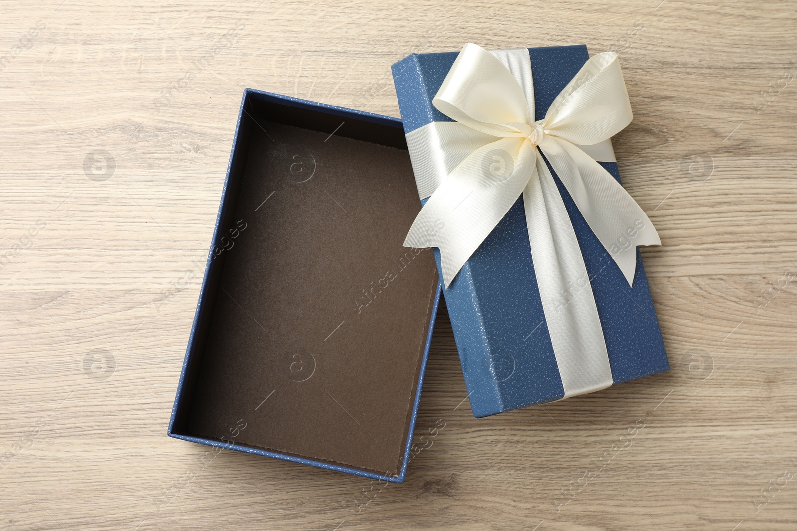 Opened gift box with beautiful lid on light wooden table, top view Photo of Opened gift box with beautiful lid on light wooden table, top view