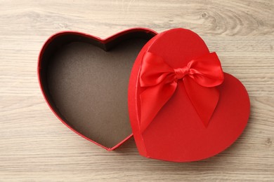 Photo of Opened heart shaped gift box on light wooden table, top view