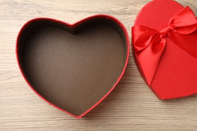 Photo of Opened heart shaped gift box on light wooden table, top view
