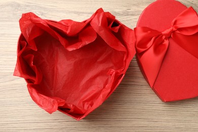 Photo of Opened heart shaped gift box on light wooden table, top view