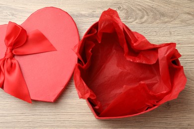 Photo of Opened heart shaped gift box on light wooden table, top view