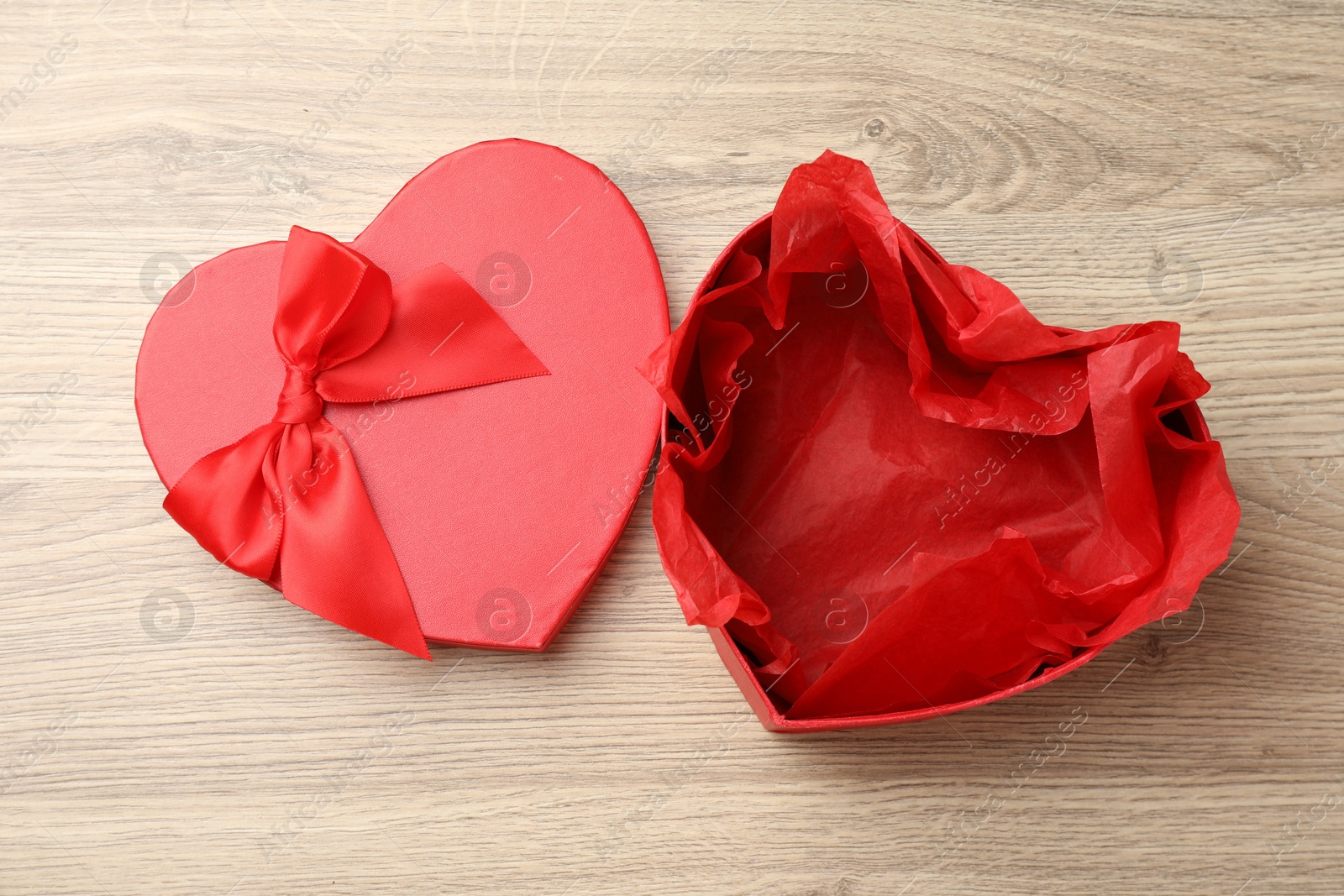 Photo of Opened heart shaped gift box on light wooden table, top view