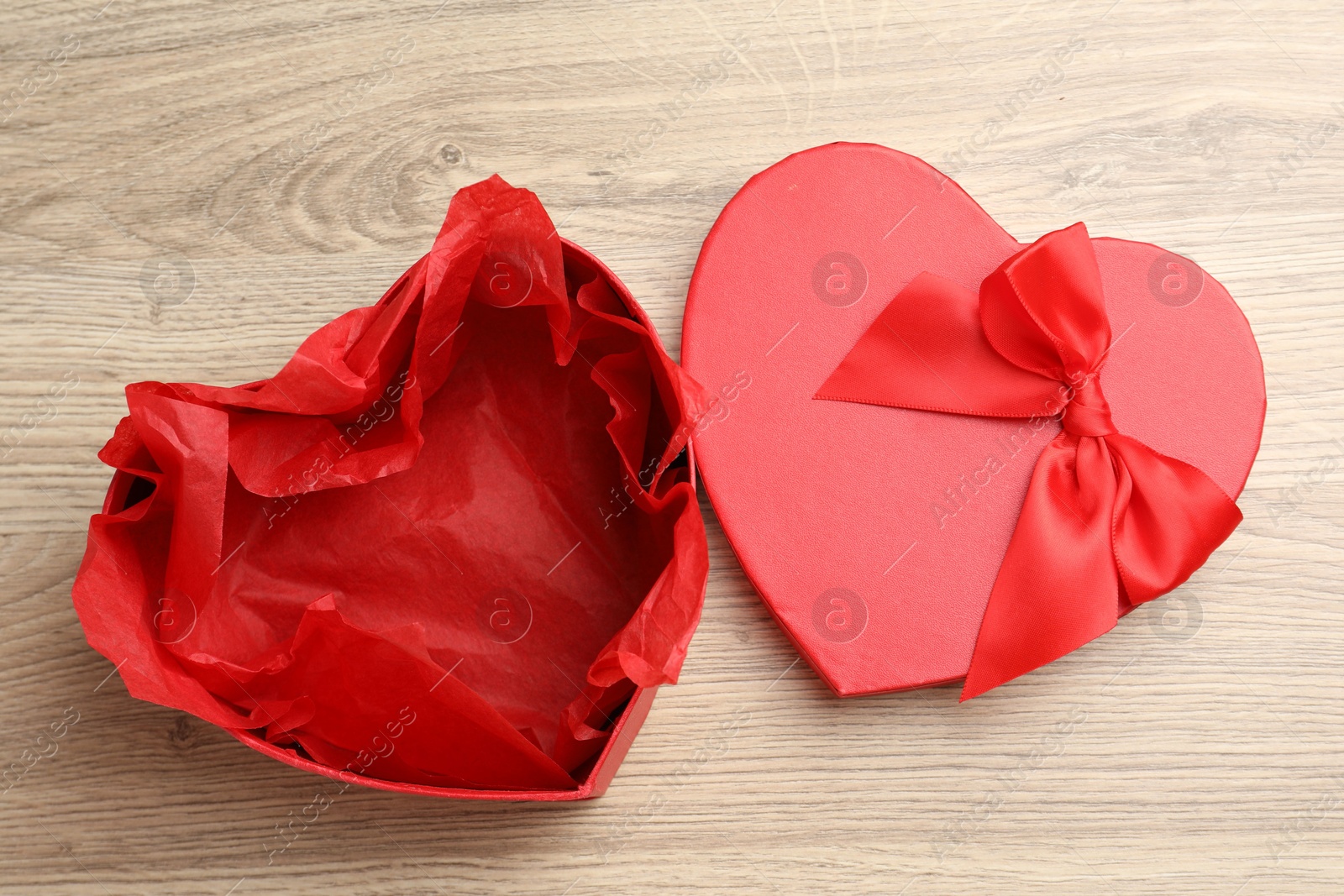 Photo of Opened heart shaped gift box on light wooden table, top view