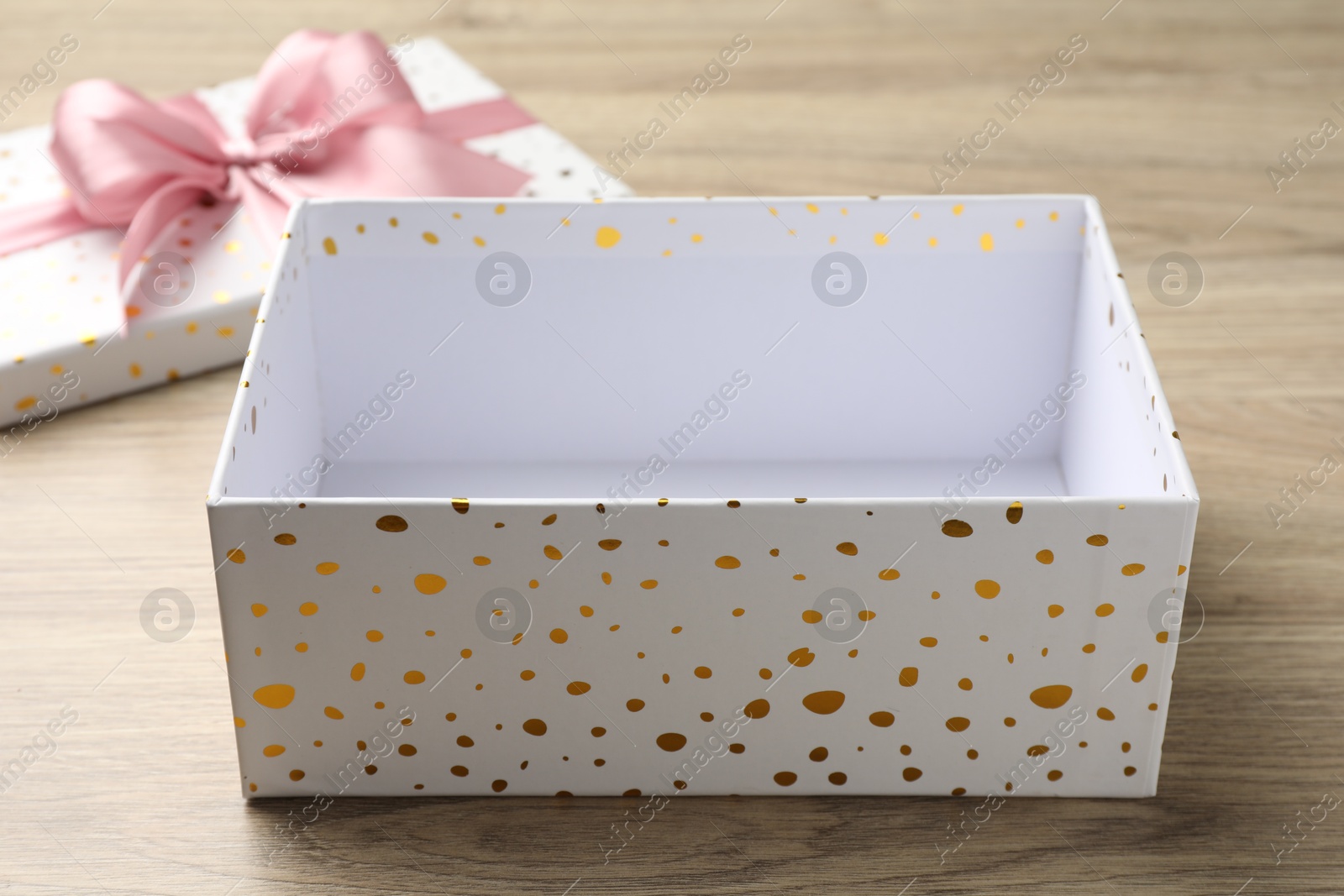 Opened gift box with beautiful lid on light wooden table, closeup Photo of Opened gift box with beautiful lid on light wooden table, closeup