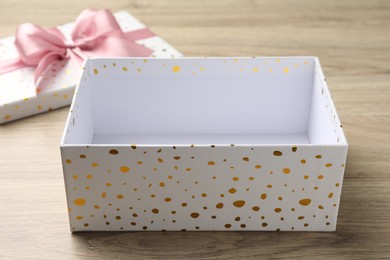 Photo of Opened gift box with beautiful lid on light wooden table, closeup
