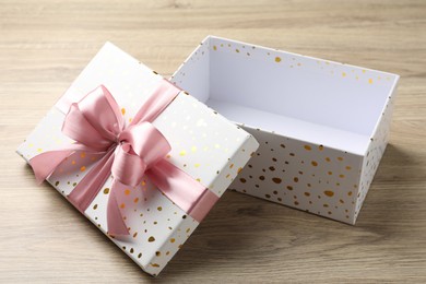 Photo of Opened gift box with beautiful lid on light wooden table, closeup