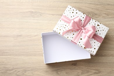 Photo of Opened gift box with beautiful lid on light wooden table, top view. Space for text