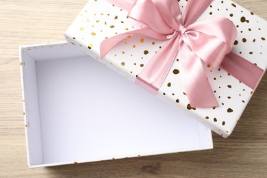 Photo of Opened gift box with beautiful lid on light wooden table, top view