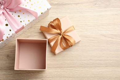 Photo of Opened and closed gift boxes on light wooden table, flat lay. Space for text