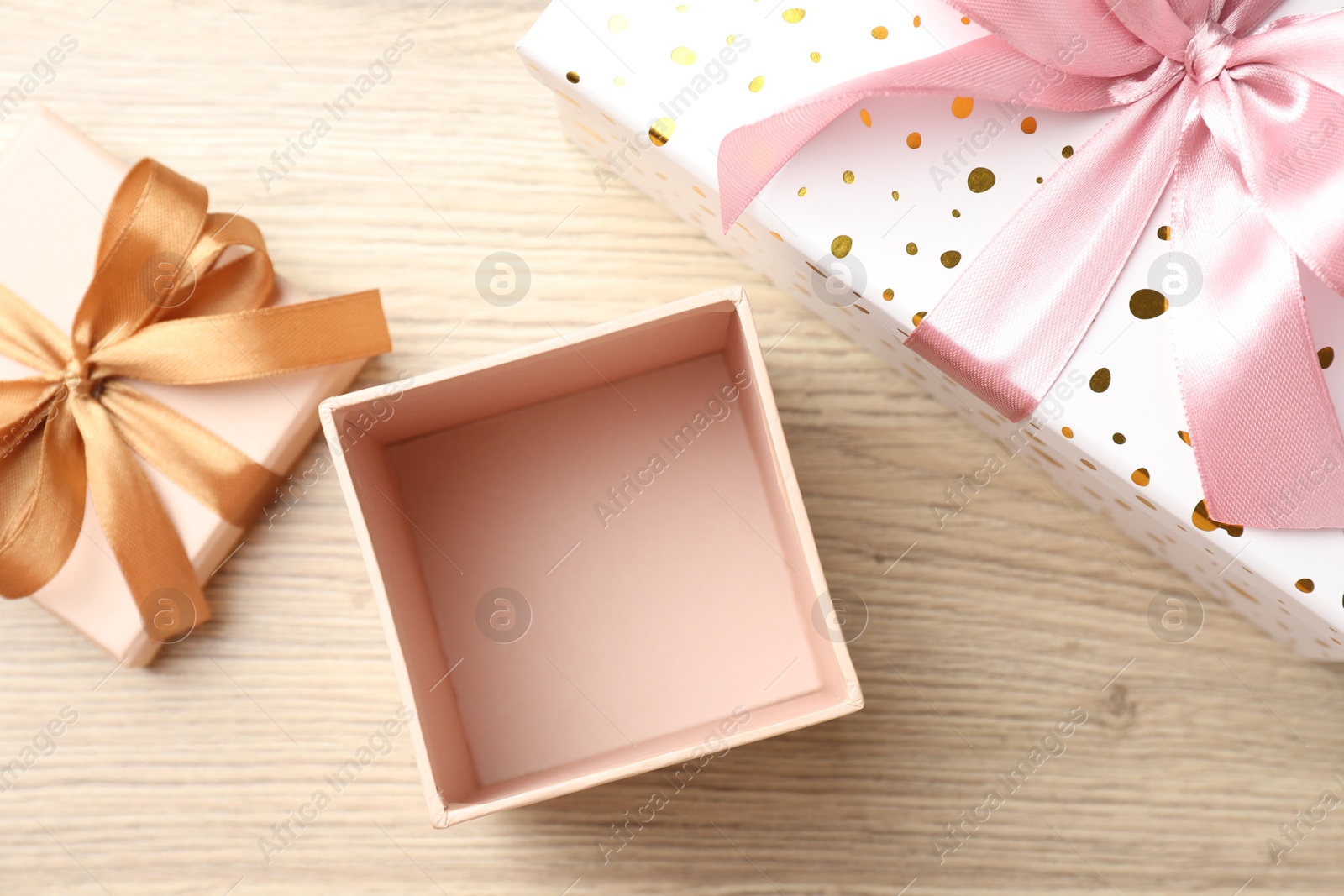 Photo of Opened and closed gift boxes on light wooden table, flat lay