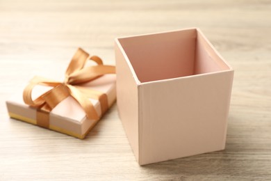 Photo of Opened gift box with beautiful lid on light wooden table, closeup