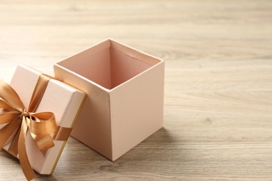 Photo of Opened gift box with beautiful lid on light wooden table, closeup. Space for text
