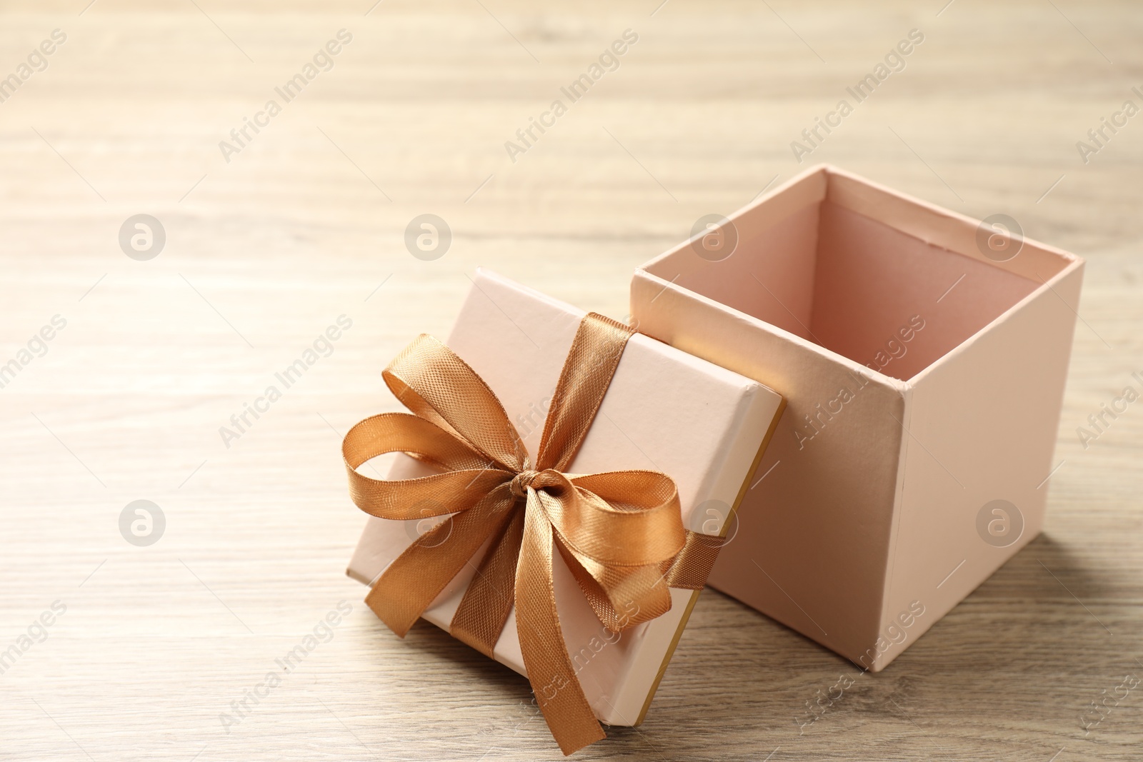 Photo of Opened gift box with beautiful lid on light wooden table, closeup. Space for text