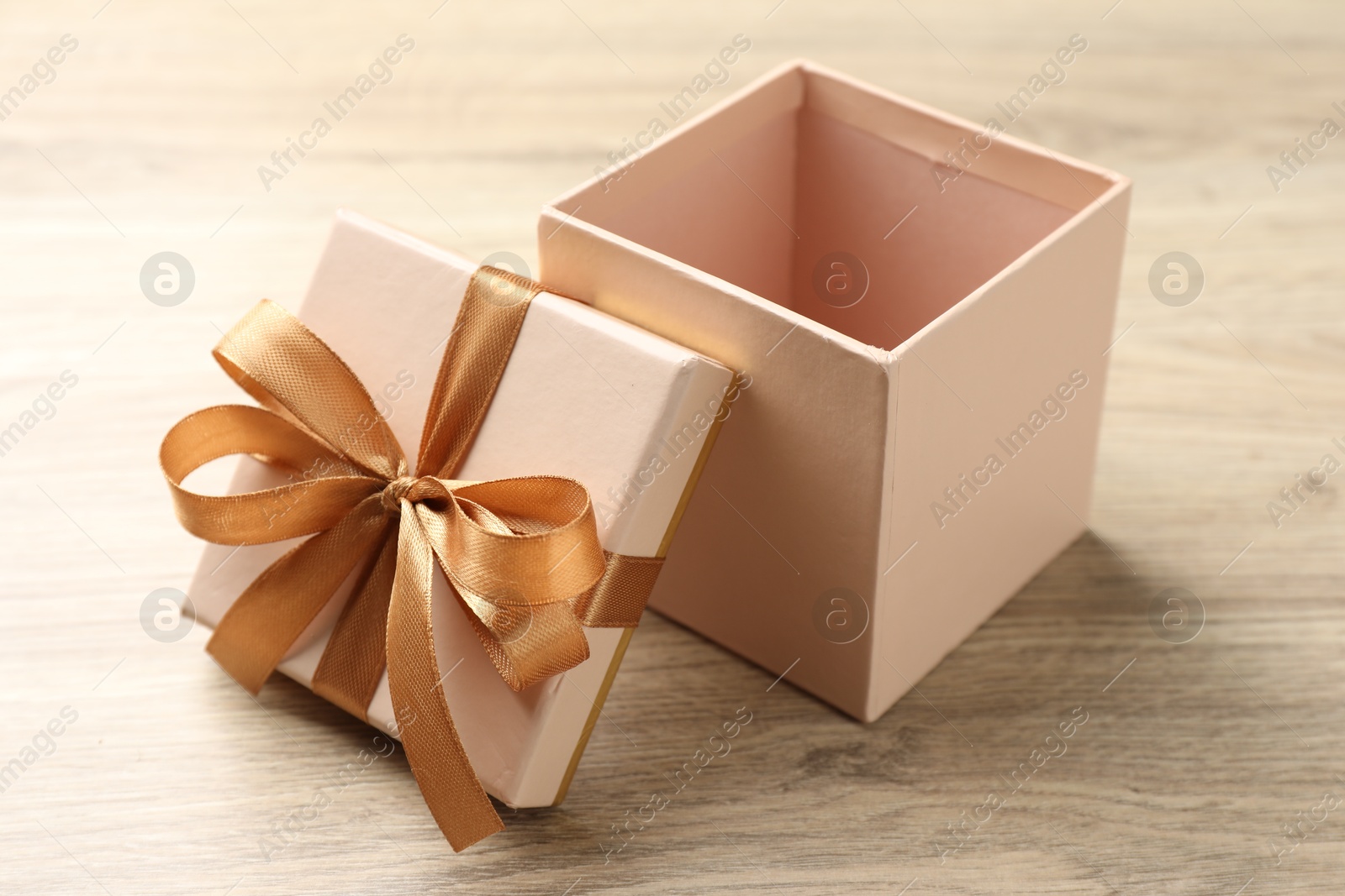 Photo of Opened gift box with beautiful lid on light wooden table, closeup