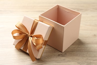 Photo of Opened gift box with beautiful lid on light wooden table, closeup