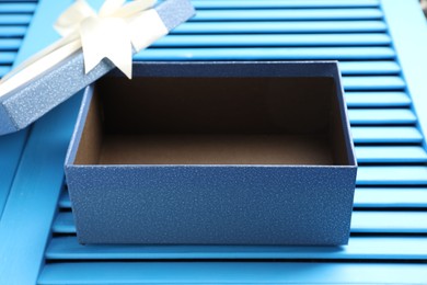 Photo of Opened gift box with beautiful lid on light blue wooden table, closeup