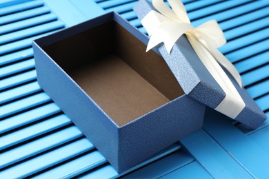 Photo of Opened gift box with beautiful lid on light blue wooden table, closeup