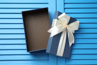 Photo of Opened gift box with beautiful lid on light blue wooden table, top view