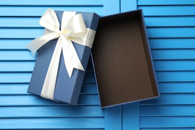 Photo of Opened gift box with beautiful lid on light blue wooden table, top view