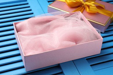 Photo of Opened gift box with beautiful lid on light blue wooden table, closeup