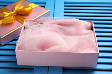 Photo of Opened gift box with beautiful lid on light blue wooden table, closeup