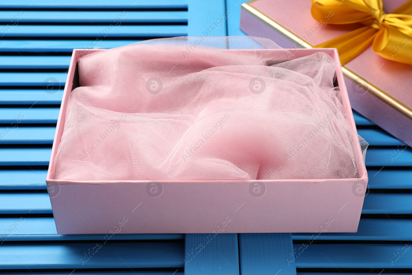 Photo of Opened gift box with beautiful lid on light blue wooden table, closeup