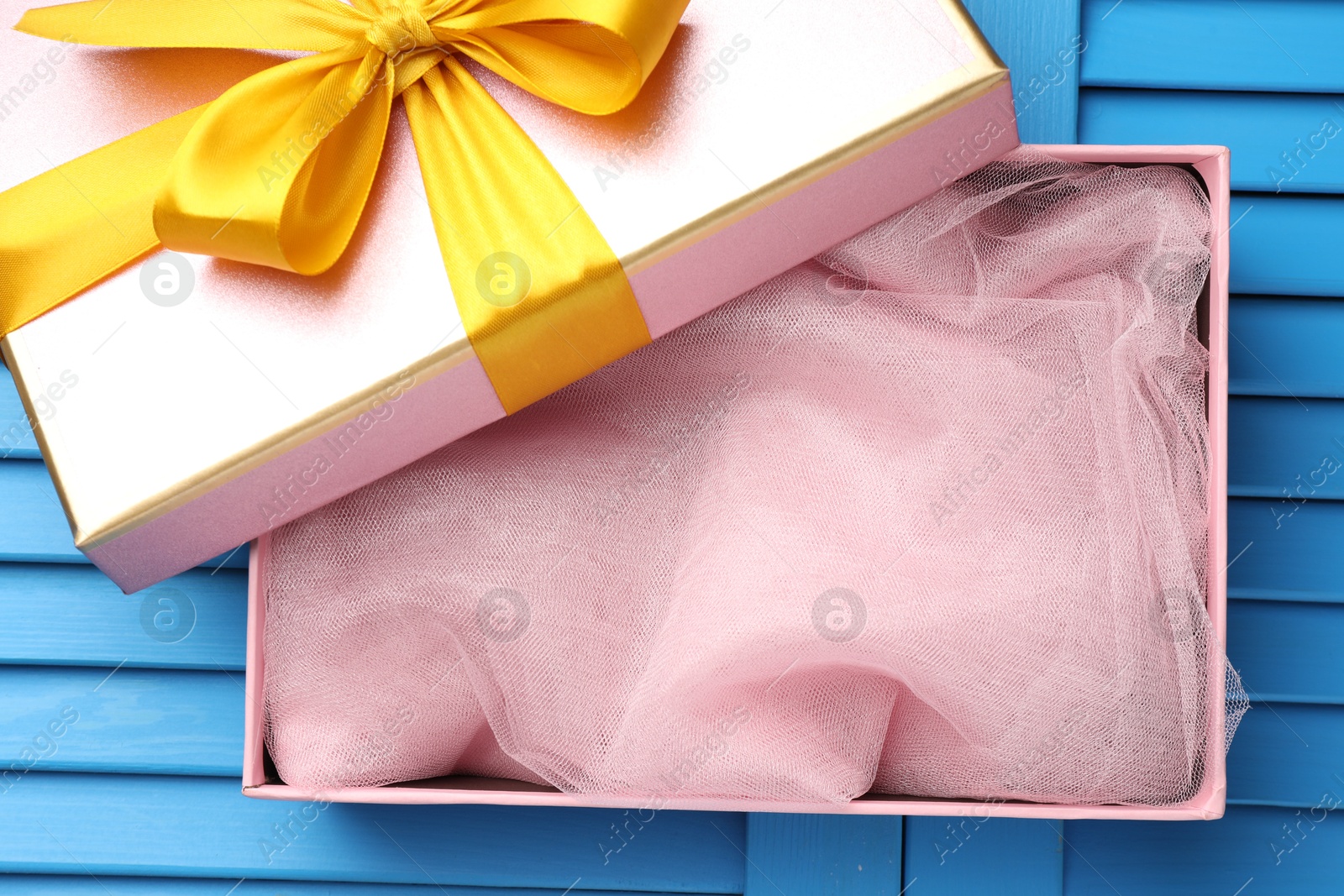 Photo of Opened gift box with beautiful lid on light blue wooden table, top view