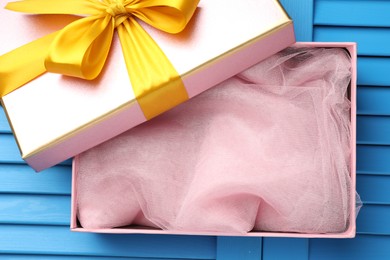 Photo of Opened gift box with beautiful lid on light blue wooden table, top view