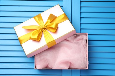 Photo of Opened gift box with beautiful lid on light blue wooden table, top view