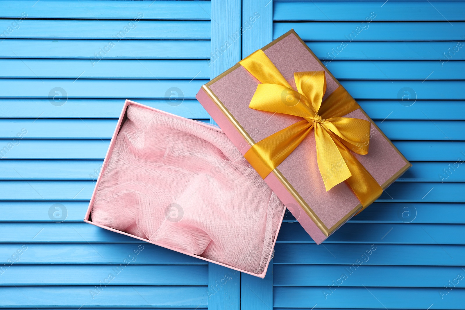 Photo of Opened gift box with beautiful lid on light blue wooden table, top view