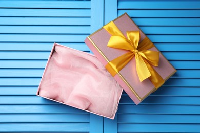 Photo of Opened gift box with beautiful lid on light blue wooden table, top view