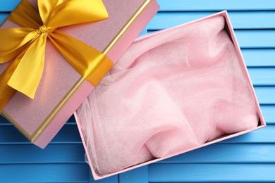 Photo of Opened gift box with beautiful lid on light blue wooden table, top view