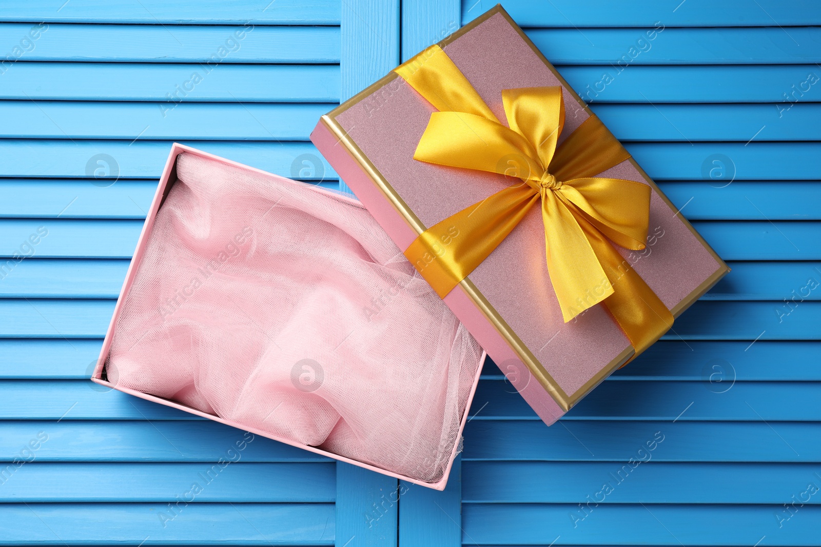 Photo of Opened gift box with beautiful lid on light blue wooden table, top view