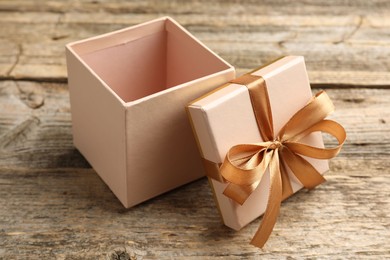 Photo of Opened gift box with beautiful lid on wooden table, closeup