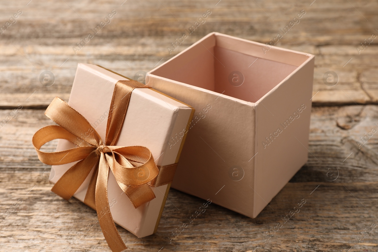 Photo of Opened gift box with beautiful lid on wooden table, closeup