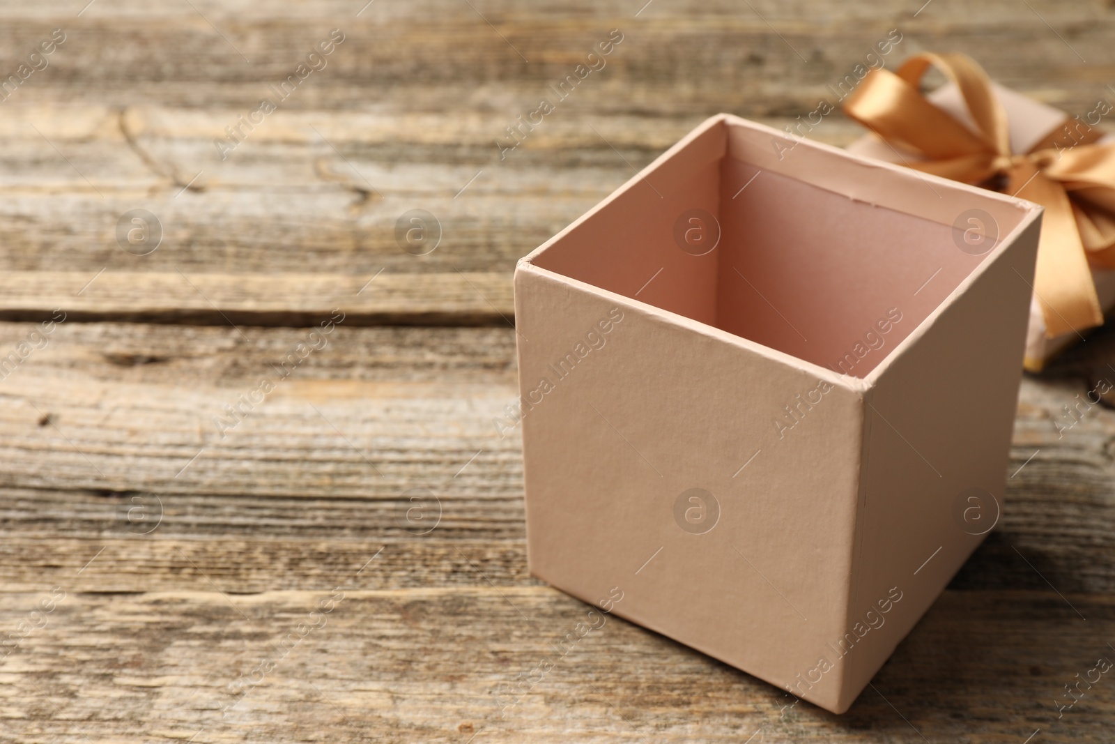 Photo of Opened gift box with beautiful lid on wooden table, closeup. Space for text