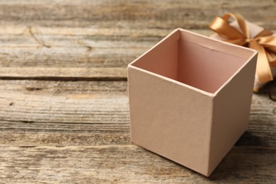 Photo of Opened gift box with beautiful lid on wooden table, closeup. Space for text