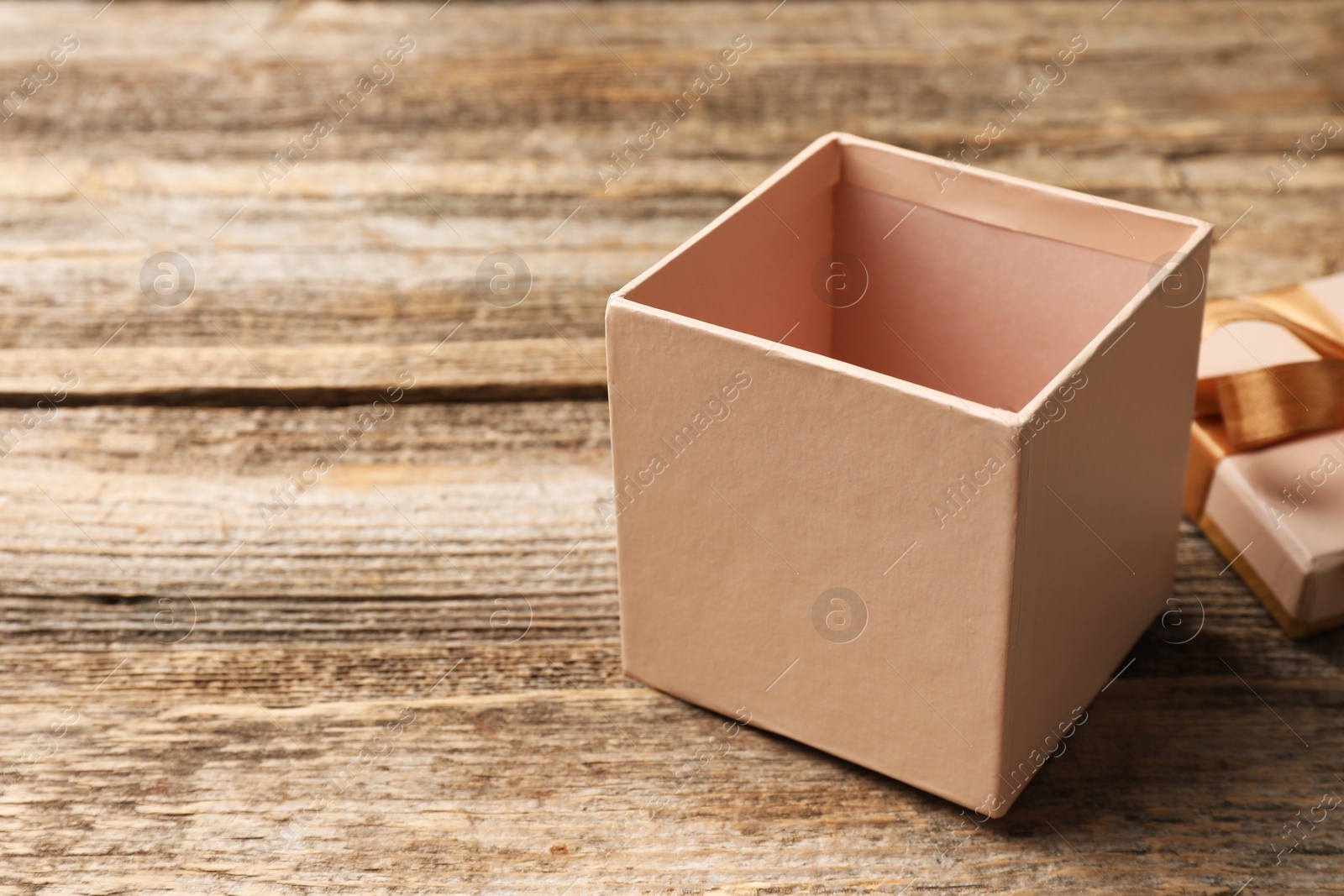 Photo of Opened gift box with beautiful lid on wooden table, closeup. Space for text
