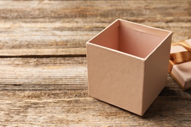 Photo of Opened gift box with beautiful lid on wooden table, closeup. Space for text