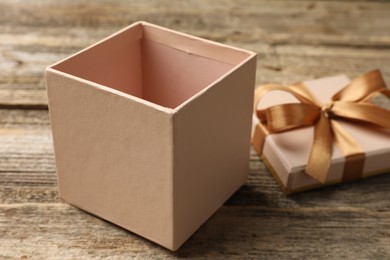 Photo of Opened gift box with beautiful lid on wooden table, closeup