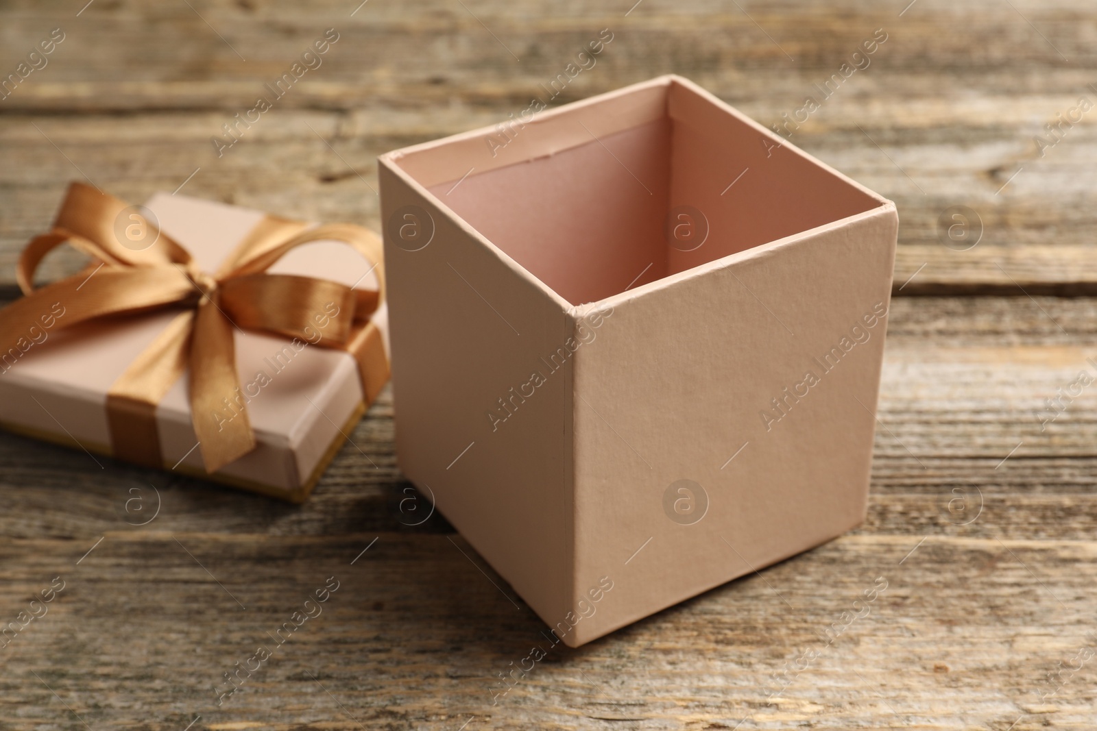 Photo of Opened gift box with beautiful lid on wooden table, closeup