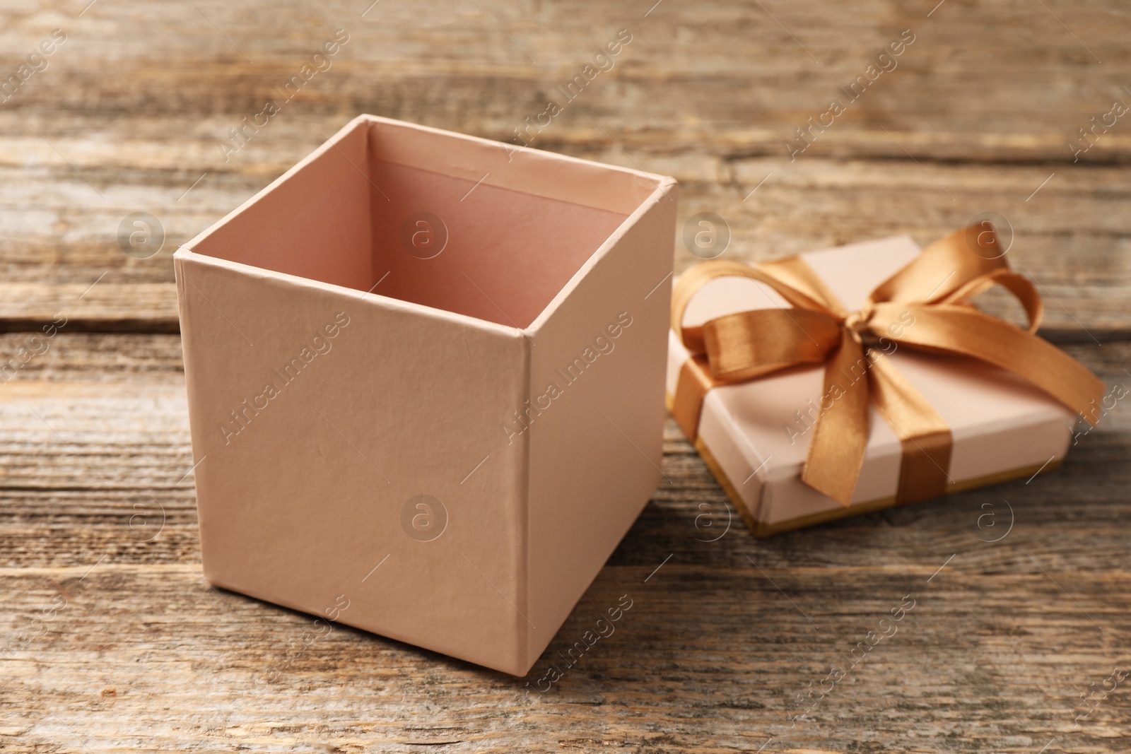 Photo of Opened gift box with beautiful lid on wooden table, closeup