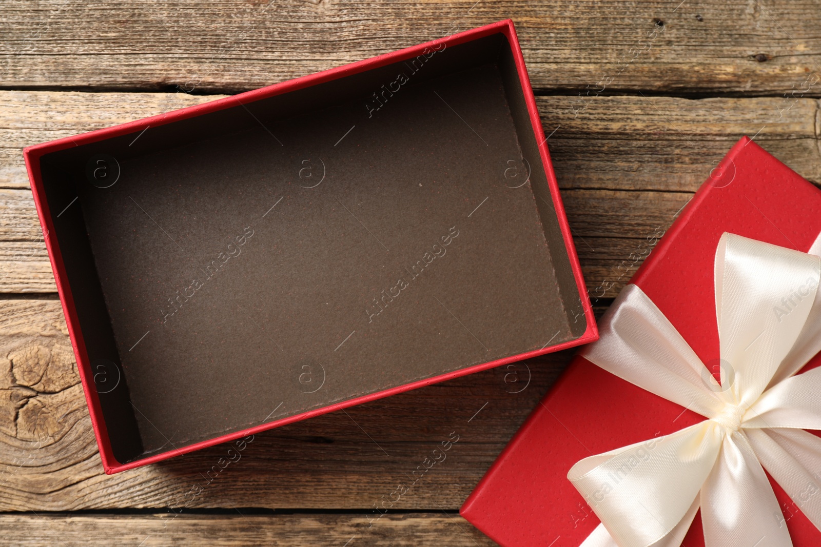 Photo of Opened gift box with beautiful lid on wooden table, top view