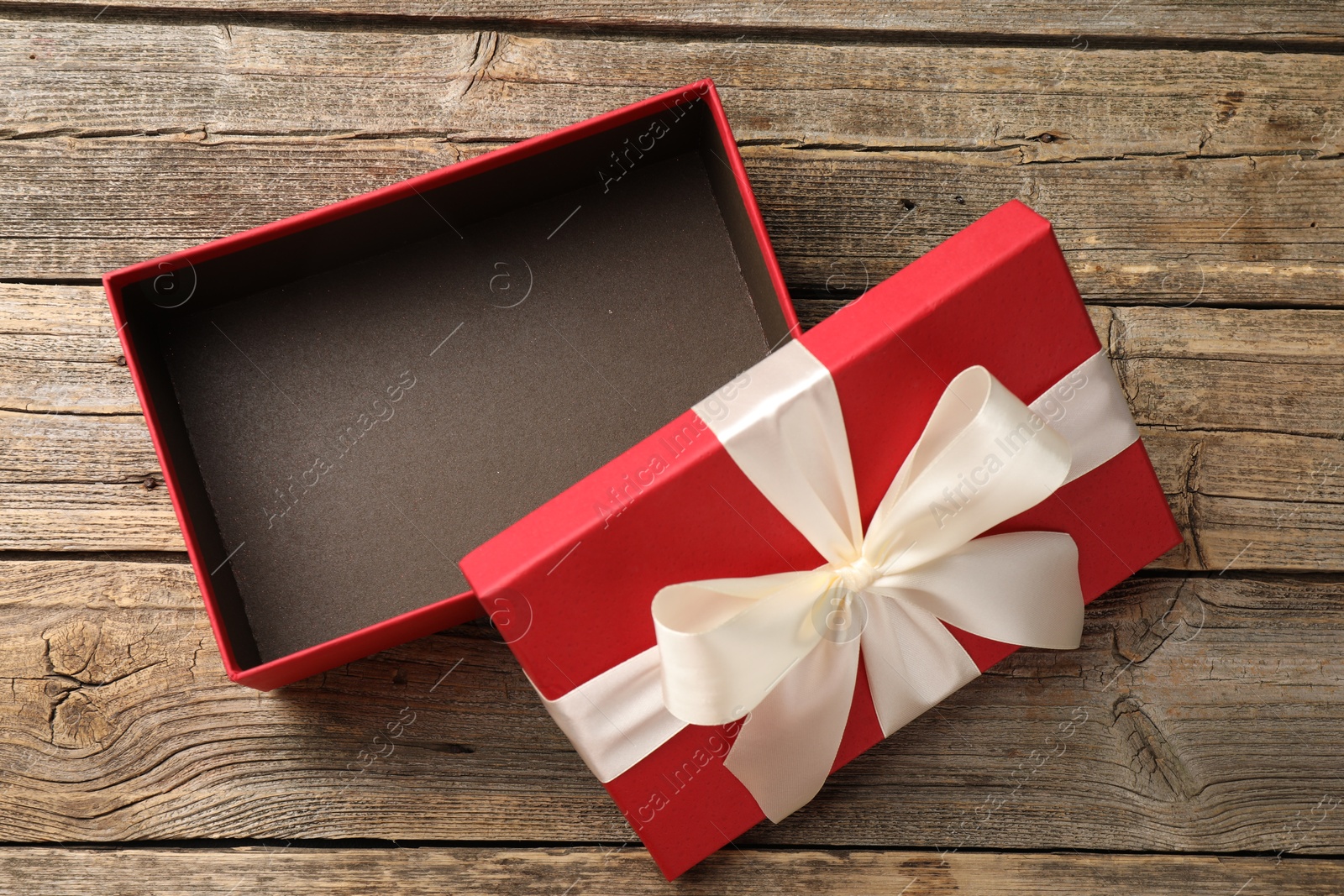 Photo of Opened gift box with beautiful lid on wooden table, top view