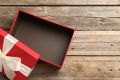 Photo of Opened gift box with beautiful lid on wooden table, top view. Space for text