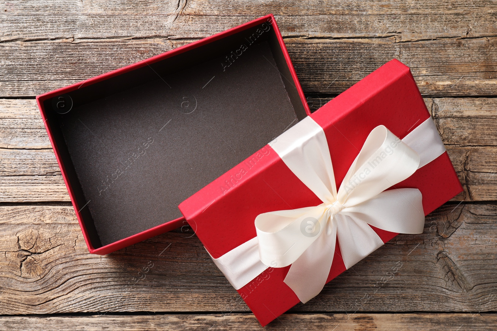 Photo of Opened gift box with beautiful lid on wooden table, top view